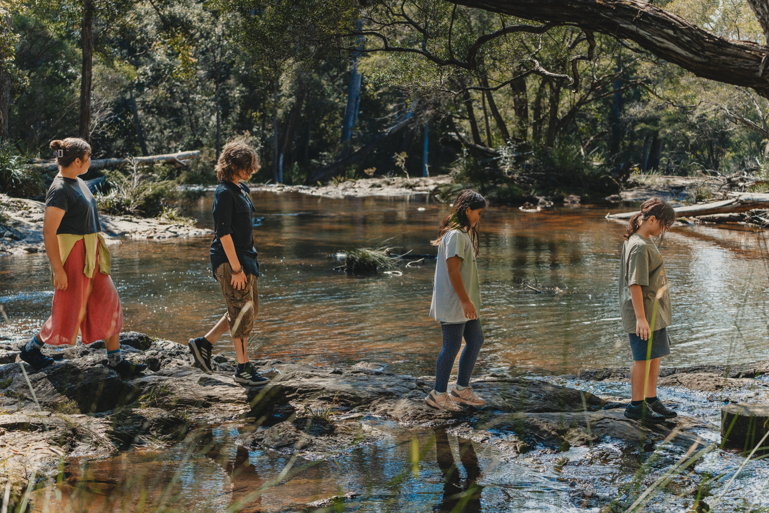 Children exploring Nature and crossing the stepping stones in Nightcap National Park